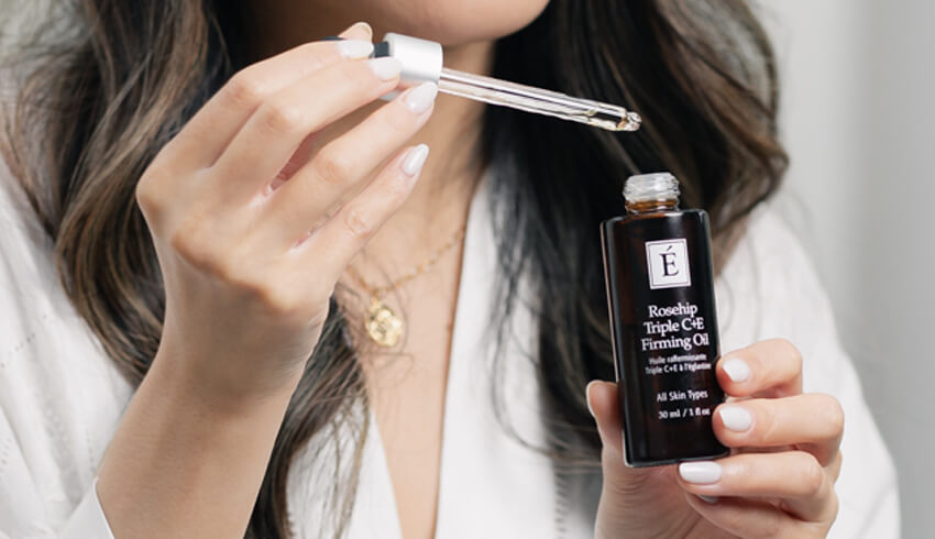 a woman applying eminence organics rosehip triple C+E firming oil